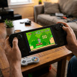 Hands holding a handheld gaming console displaying a Super Mario video game