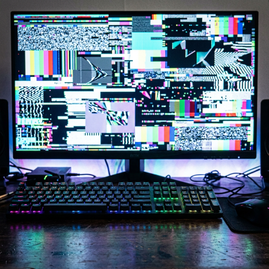 Open PlayStation 5 game case for Quantum Disruption with a computer monitor in the background showing colorful screen glitch patterns.